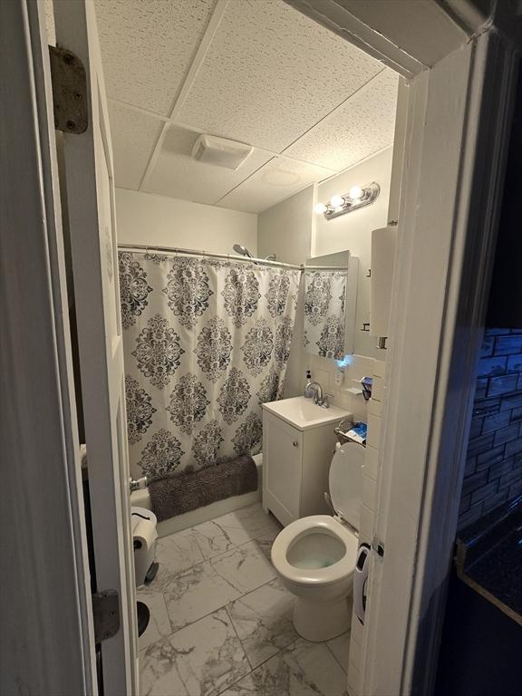 bathroom featuring a paneled ceiling, vanity, toilet, and a shower with shower curtain