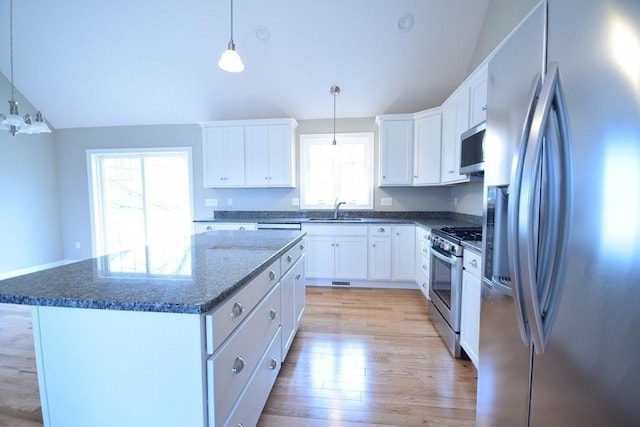 kitchen with stainless steel appliances, a kitchen island, white cabinets, and decorative light fixtures