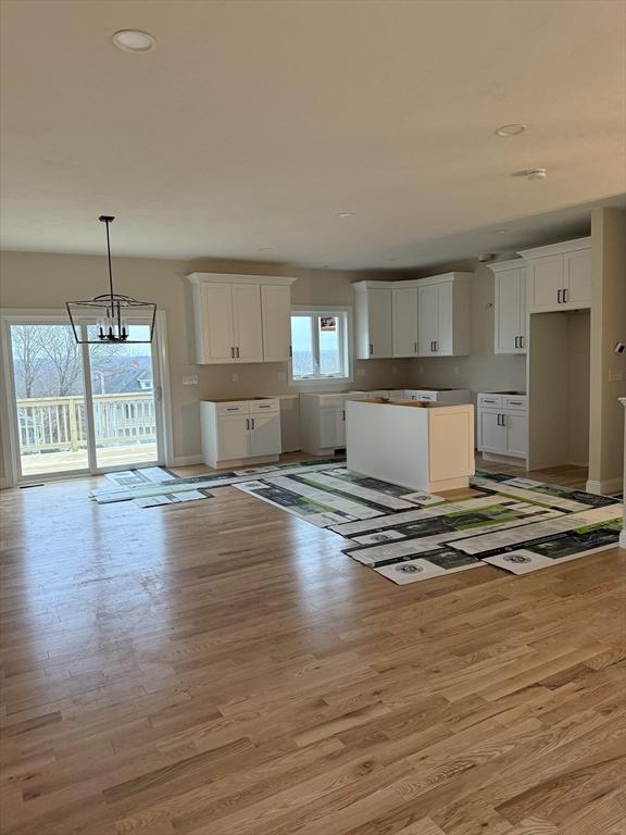 kitchen with white cabinetry, a notable chandelier, decorative light fixtures, and light hardwood / wood-style floors