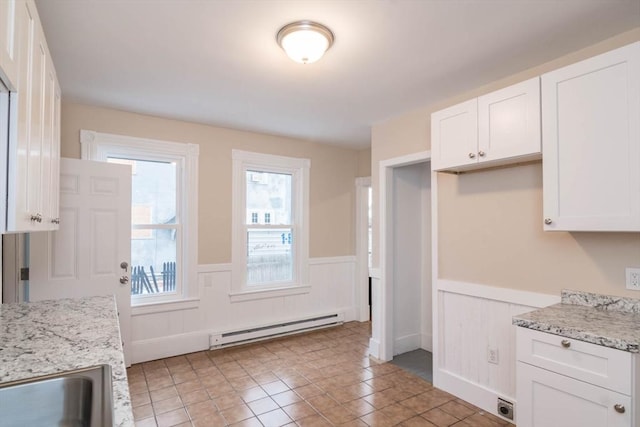 kitchen featuring light stone counters, plenty of natural light, white cabinets, and a baseboard radiator