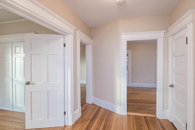 corridor with light hardwood / wood-style floors and crown molding