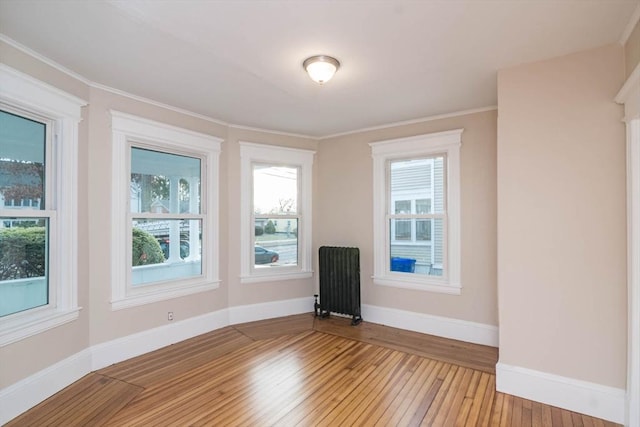 unfurnished room featuring light wood-type flooring, radiator heating unit, and crown molding