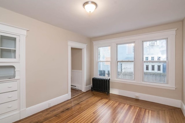 unfurnished room featuring baseboard heating, radiator, and light hardwood / wood-style floors