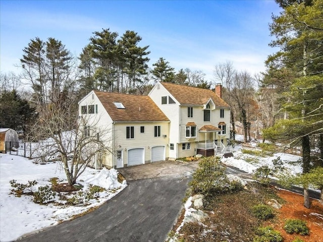 view of front of house with aphalt driveway, a chimney, and an attached garage