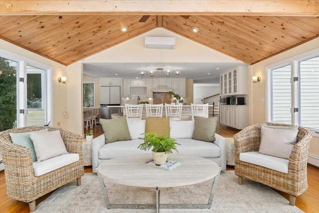 living room with light wood-type flooring, a healthy amount of sunlight, lofted ceiling with beams, and a wall mounted AC