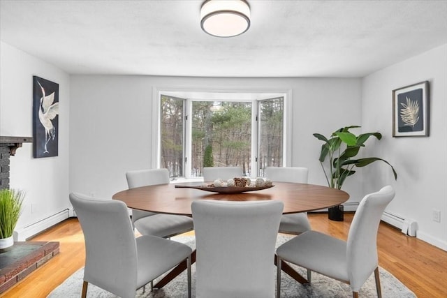 dining area with baseboards, a baseboard radiator, and light wood-style floors