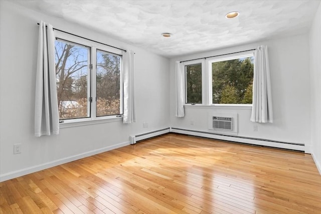 unfurnished room with plenty of natural light, light wood-style flooring, baseboards, and a wall mounted AC