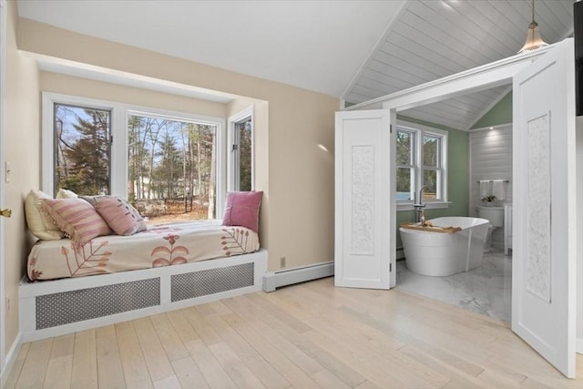 bedroom featuring a baseboard heating unit, lofted ceiling, light wood-style flooring, and baseboard heating