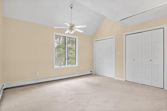 unfurnished bedroom with lofted ceiling, light colored carpet, baseboard heating, two closets, and attic access