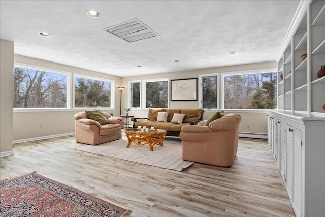 living room featuring light wood-type flooring, a baseboard radiator, a healthy amount of sunlight, and recessed lighting