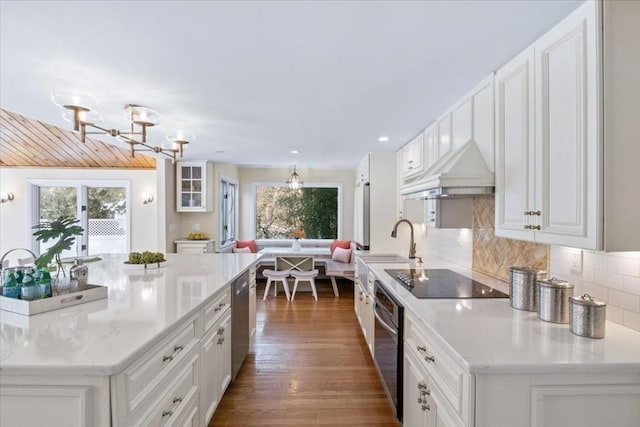 kitchen with custom exhaust hood, white cabinetry, appliances with stainless steel finishes, and glass insert cabinets