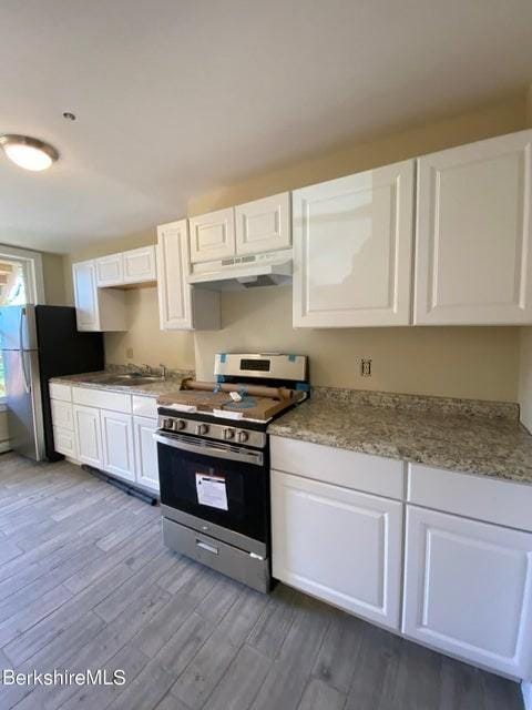 70-72 Chase Ave, North Adams, MA 01247 - kitchen with stainless steel appliances, under cabinet range hood, dark wood-style flooring, and white cabinetry