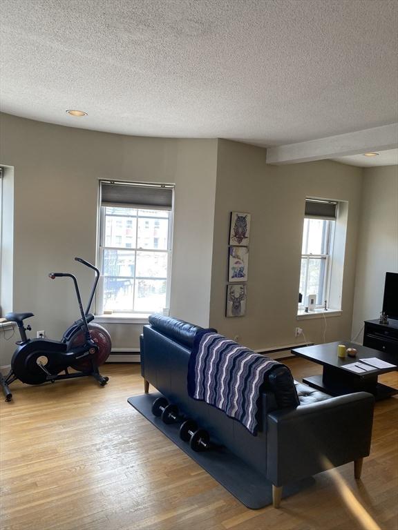 living area featuring wood finished floors, a textured ceiling, and a wealth of natural light