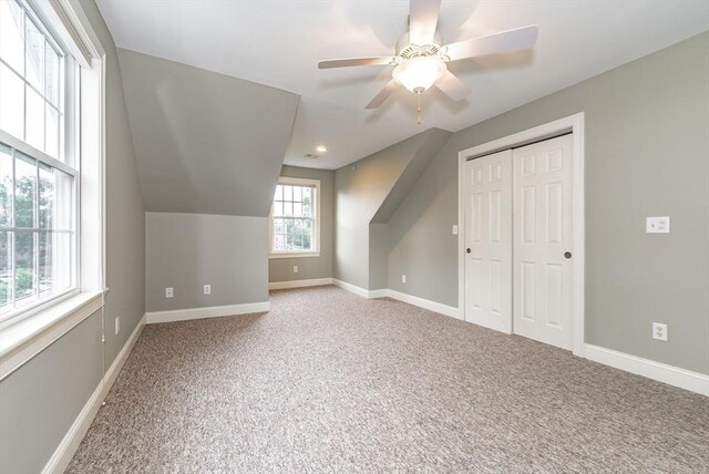 additional living space with lofted ceiling, ceiling fan, and light colored carpet