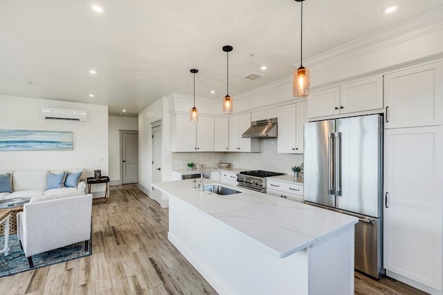 2-6 Market St Unit 3, Newburyport, MA 01950 - kitchen with high quality appliances, ventilation hood, a wall mounted air conditioner, white cabinets, and light wood-type flooring