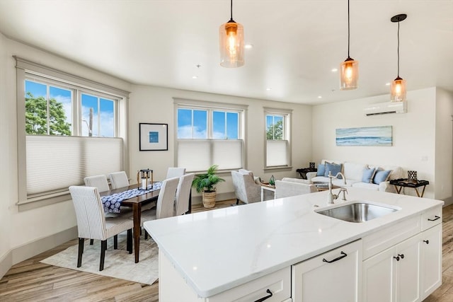 2-6 Market St Unit 3, Newburyport, MA 01950 - kitchen with a wall unit AC, open floor plan, light wood-style flooring, white cabinetry, and pendant lighting