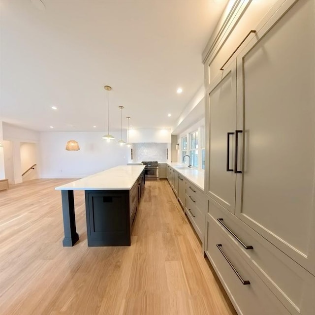 8A Milk St Unit 1, Newburyport, MA 01950 - kitchen featuring light countertops, a kitchen island, light wood finished floors, stainless steel gas range, and pendant lighting