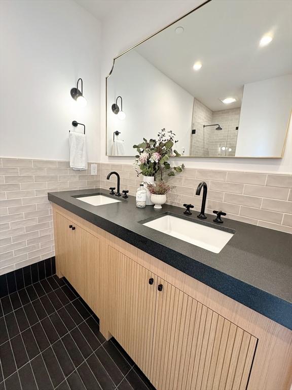 8A Milk St Unit 1, Newburyport, MA 01950 - bathroom with double vanity, tile walls, tile patterned floors, tiled shower, and recessed lighting