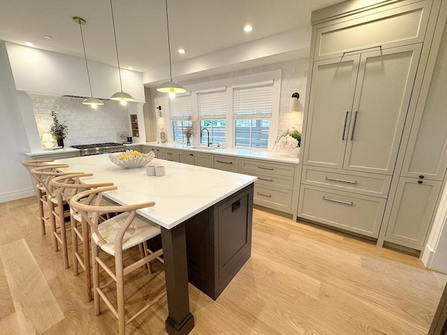 8A Milk St Unit 1, Newburyport, MA 01950 - kitchen with tasteful backsplash, light wood-type flooring, a breakfast bar area, a center island, and recessed lighting