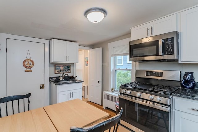16 Fairfield Ave, Northampton, MA 01062 - kitchen with stainless steel appliances, radiator, a sink, white cabinetry, and dark stone counters