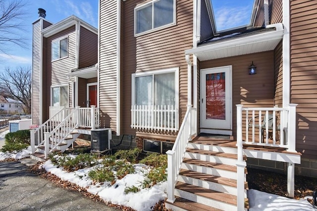 snow covered property entrance with central AC