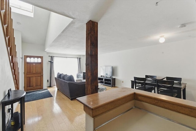 living area with light wood finished floors, stairway, and a skylight