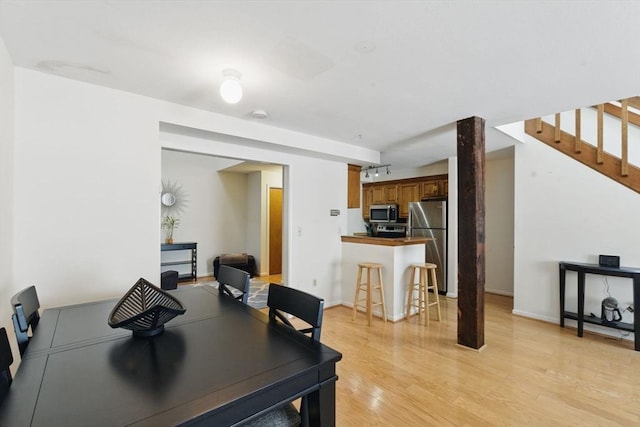 dining area with stairway, light wood-style flooring, and baseboards