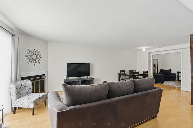 living room featuring light wood finished floors and a glass covered fireplace