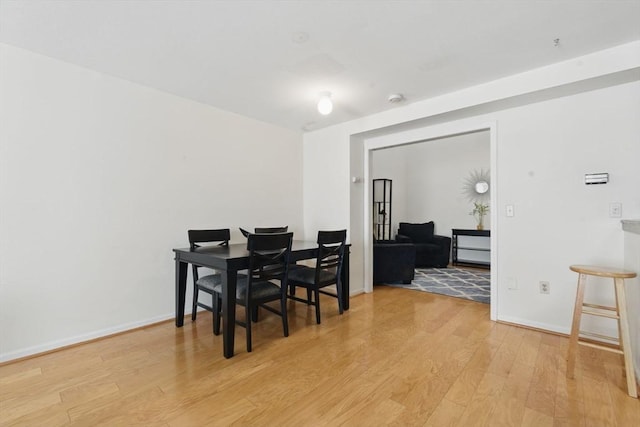 dining space featuring light wood-style flooring and baseboards