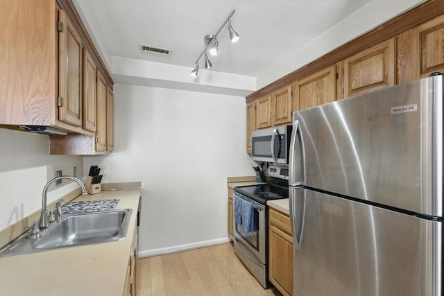 kitchen featuring stainless steel appliances, a sink, visible vents, light countertops, and light wood-type flooring