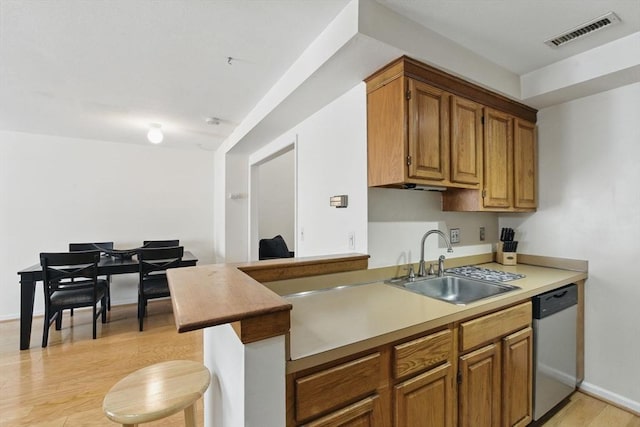 kitchen featuring visible vents, dishwasher, brown cabinets, light wood-style floors, and a sink