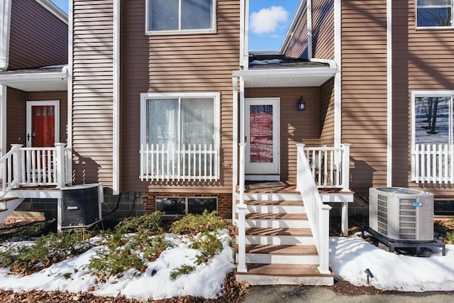 snow covered property entrance with central air condition unit