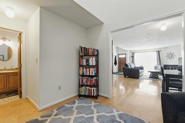 corridor with a sink, light wood-style flooring, and baseboards