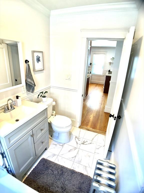 22-24 Ellison Ave Unit 1, Boston, MA 02126 - half bathroom with ornamental molding, vanity, marble look tile flooring, and radiator