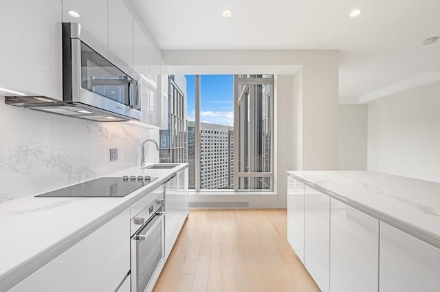 kitchen featuring light wood finished floors, stainless steel appliances, recessed lighting, white cabinetry, and modern cabinets