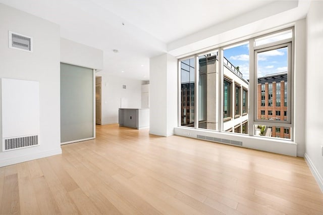 empty room with baseboards, wood finished floors, and visible vents
