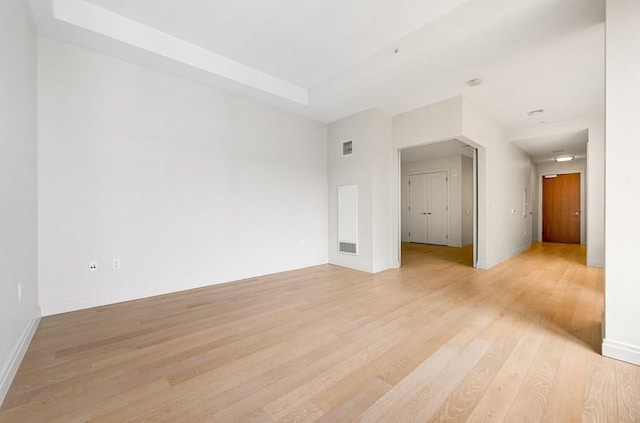 unfurnished room with visible vents, light wood-style flooring, and baseboards