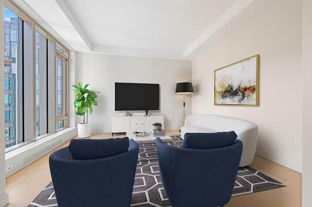 living room featuring baseboards, a tray ceiling, and wood finished floors