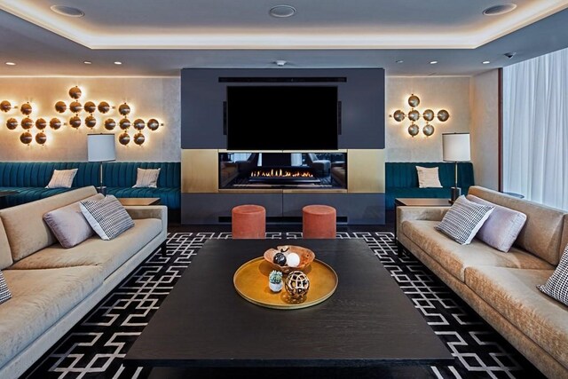 living room featuring a multi sided fireplace and a tray ceiling