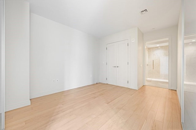 unfurnished bedroom featuring visible vents, baseboards, light wood-style flooring, and ensuite bath