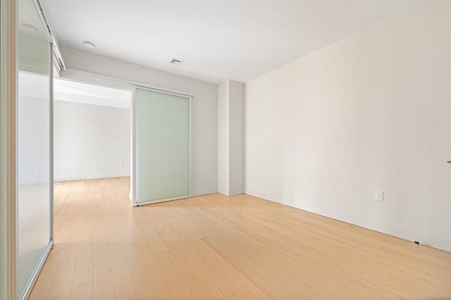 unfurnished room featuring baseboards, visible vents, and light wood-style flooring