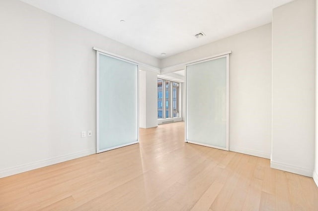 unfurnished room with light wood-type flooring, baseboards, and visible vents