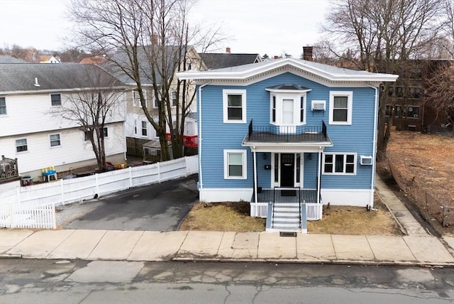 view of front of home with an AC wall unit, aphalt driveway, a porch, fence, and a chimney