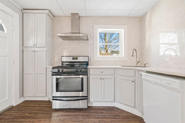 kitchen with dishwasher, wall chimney exhaust hood, stainless steel range with gas cooktop, a paneled ceiling, and white cabinets