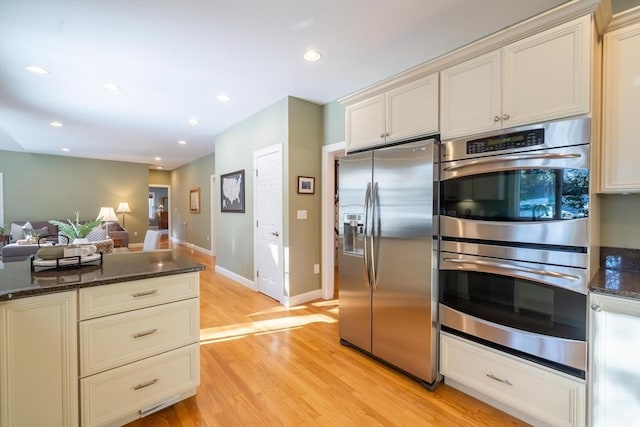 kitchen featuring stainless steel appliances, light hardwood / wood-style floors, and dark stone counters