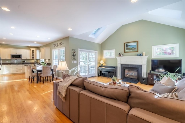 living room featuring a tiled fireplace, light hardwood / wood-style flooring, and lofted ceiling