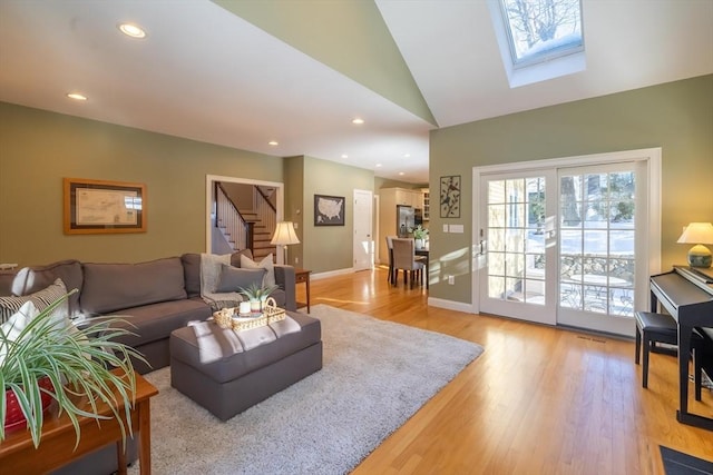 living room with plenty of natural light, vaulted ceiling with skylight, and light hardwood / wood-style flooring