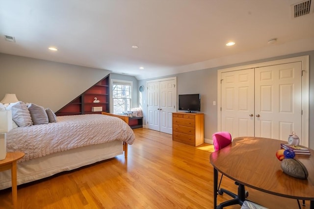 bedroom with two closets and light hardwood / wood-style flooring