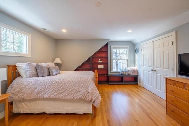 bedroom featuring lofted ceiling, a closet, and light wood-type flooring