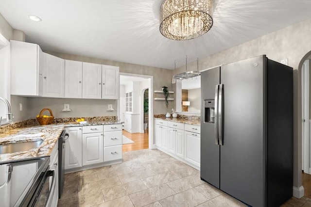 56 Beach St, Woburn, MA 01801 - kitchen with stainless steel fridge, white cabinetry, and light stone counters